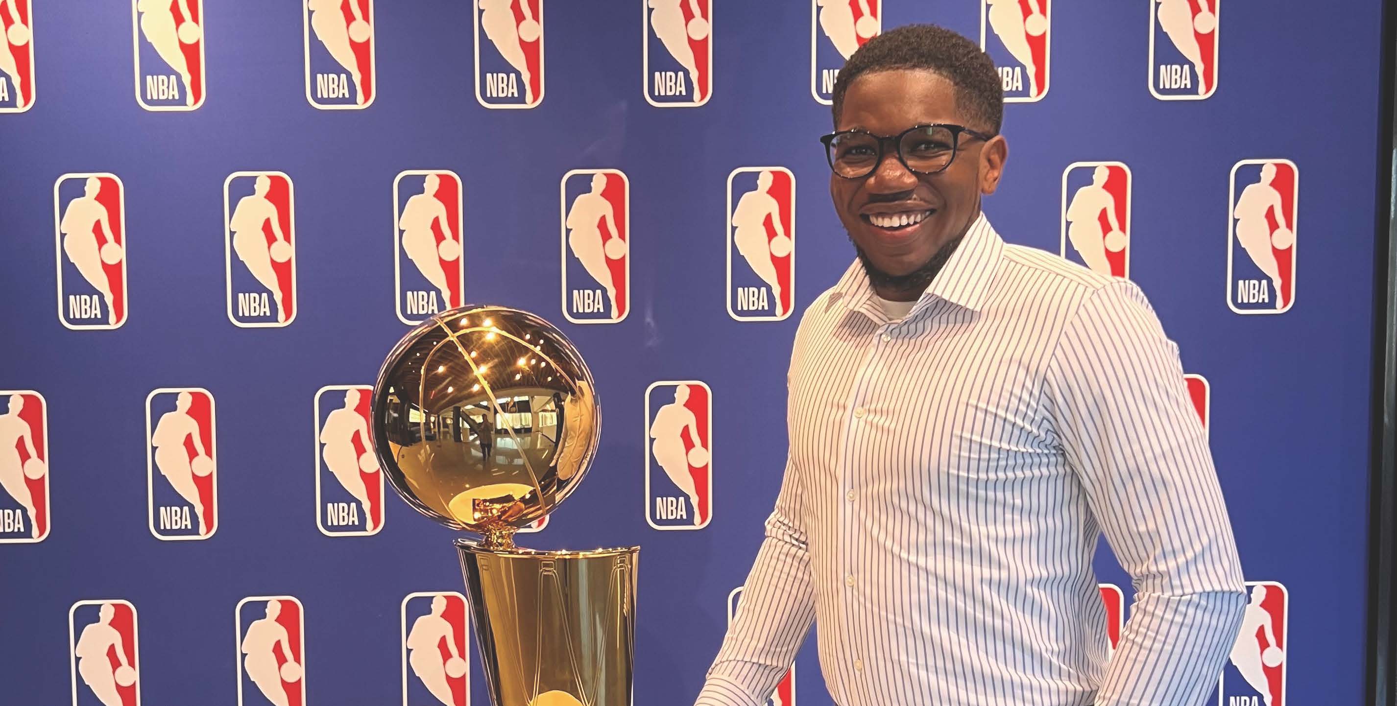 NYSCAS alum Jade Daniels standing next to NBA trophy in front of NBA step and repeat.