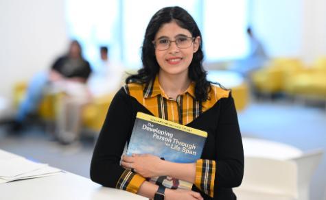 Female student smiling while holding psychology textbook