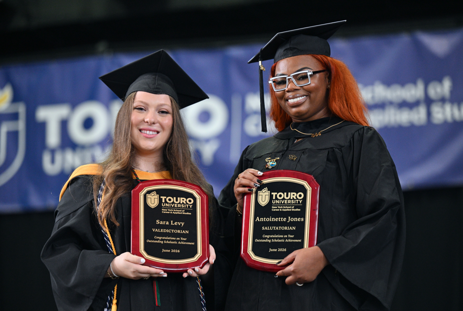 NYSCAS Valedictorian Sara Levy and Salutatorian Antoinette Jones wearing their cap and gowns on stage at the 52nd annual commencement ceremony.